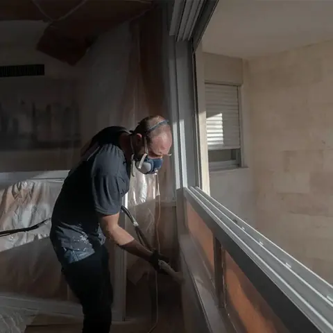 Painter spray finishing an aluminum frame on site
